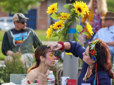 A woman has her face painted by a woman at the Eastern European music festival.